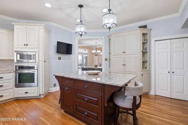 kitchen featuring light wood-style flooring, a kitchen bar, appliances with stainless steel finishes, and crown molding