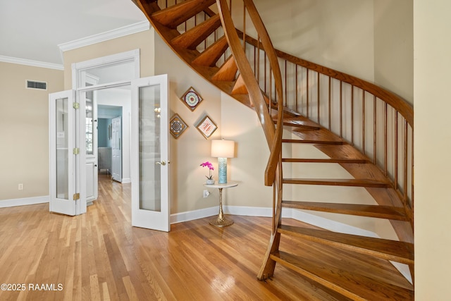 stairs with wood finished floors, visible vents, baseboards, french doors, and ornamental molding