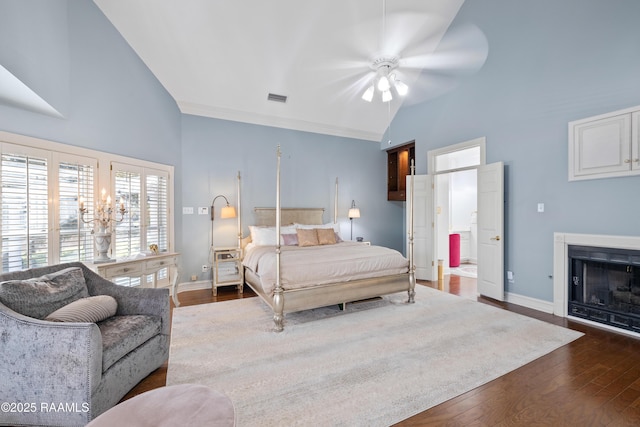 bedroom featuring a fireplace, visible vents, dark wood-type flooring, vaulted ceiling, and baseboards