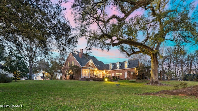 view of front of property featuring brick siding and a lawn