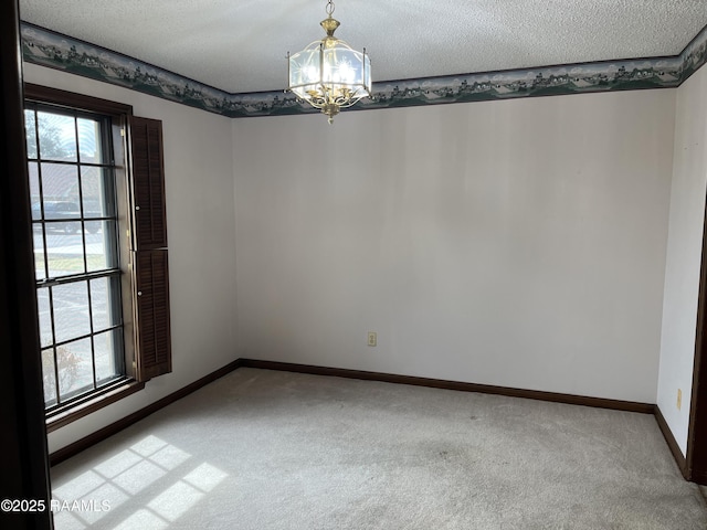 empty room featuring light carpet, an inviting chandelier, baseboards, and a textured ceiling