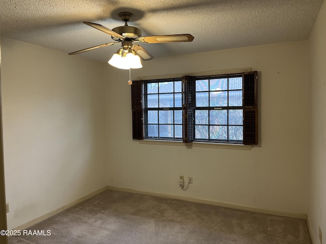 empty room with light carpet, a textured ceiling, a ceiling fan, and baseboards