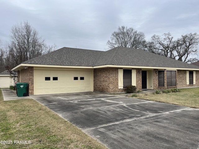 ranch-style house featuring brick siding, roof with shingles, concrete driveway, a front yard, and a garage