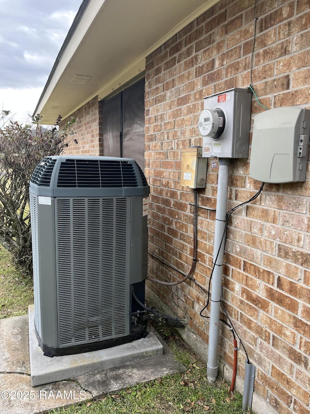 exterior details featuring central AC, brick siding, and electric meter