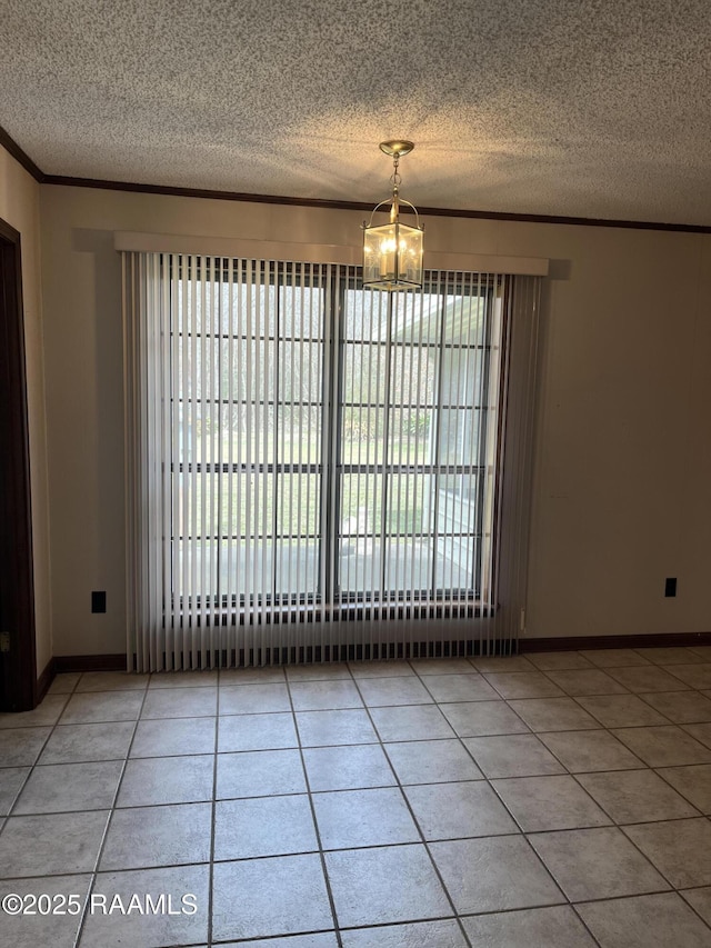 spare room featuring baseboards, ornamental molding, a textured ceiling, and tile patterned floors