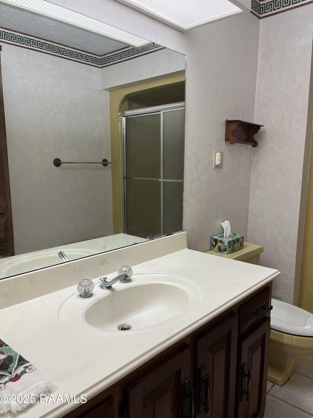 bathroom featuring toilet, a stall shower, vanity, and tile patterned floors