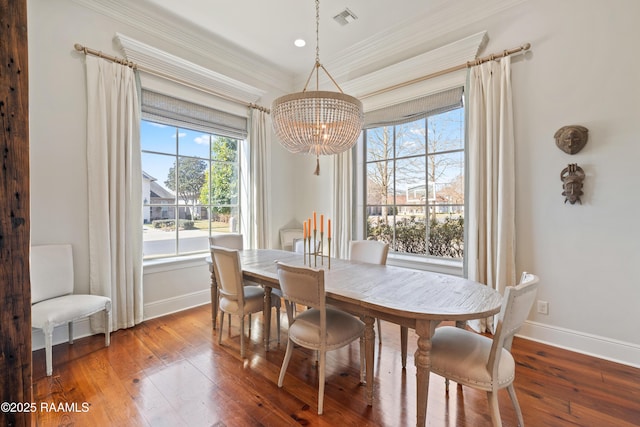 dining area featuring baseboards, visible vents, hardwood / wood-style floors, crown molding, and a chandelier