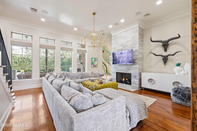 living area featuring ornamental molding, wood finished floors, visible vents, and a premium fireplace