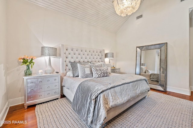 bedroom with lofted ceiling, wood finished floors, visible vents, and baseboards