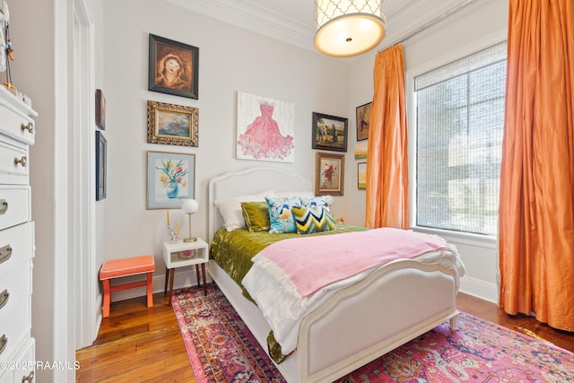 bedroom featuring hardwood / wood-style floors, baseboards, and crown molding