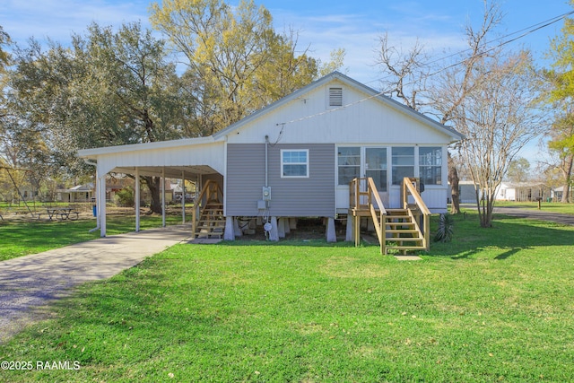 404 Senior Aly, Abbeville, LA 70510 - rear view of house featuring a lawn, driveway, a sunroom, an attached carport, and stairs