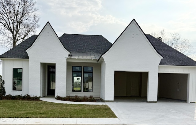 modern farmhouse style home featuring metal roof, a garage, board and batten siding, a standing seam roof, and a front yard