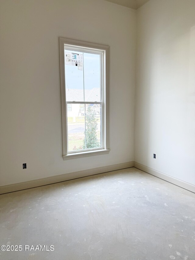 spare room with baseboards and unfinished concrete floors