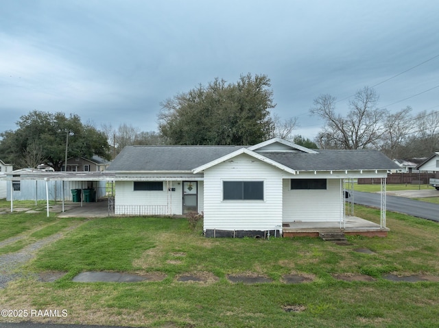 back of property featuring a carport, a yard, and a shingled roof