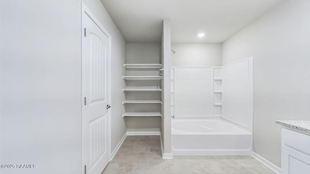 bathroom featuring a closet, vanity, baseboards, and bathing tub / shower combination