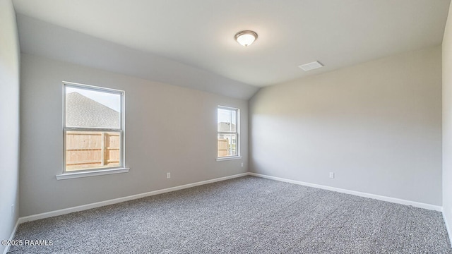 carpeted spare room featuring lofted ceiling, visible vents, and baseboards