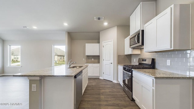 kitchen with visible vents, appliances with stainless steel finishes, dark wood-type flooring, a kitchen island with sink, and a sink