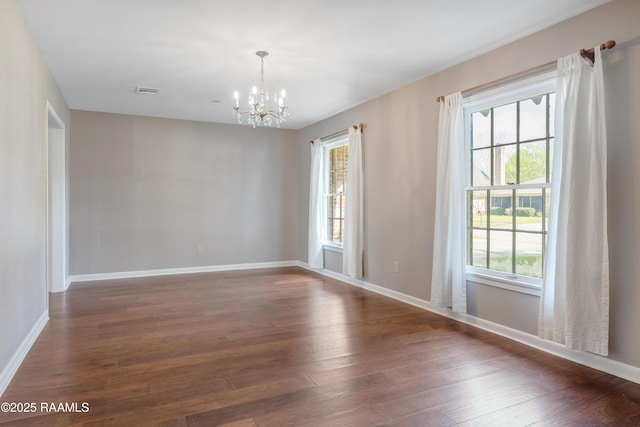 empty room with visible vents, baseboards, a notable chandelier, and dark wood-style floors