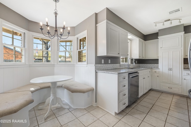 kitchen featuring visible vents, a sink, stainless steel dishwasher, white cabinetry, and a chandelier