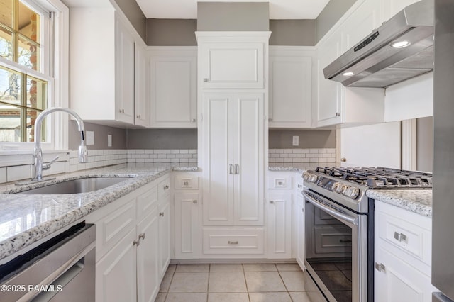 kitchen with light tile patterned floors, a sink, stainless steel appliances, white cabinets, and under cabinet range hood