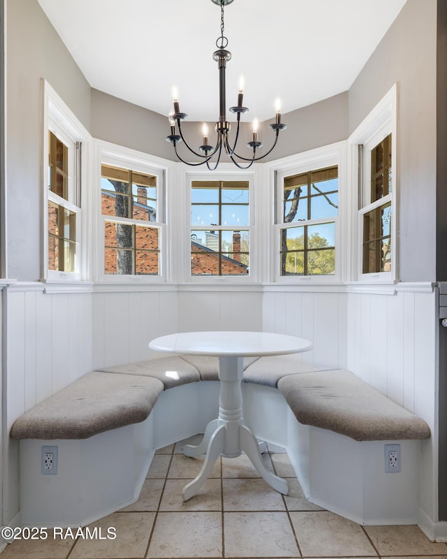 dining area with breakfast area, a wainscoted wall, and an inviting chandelier