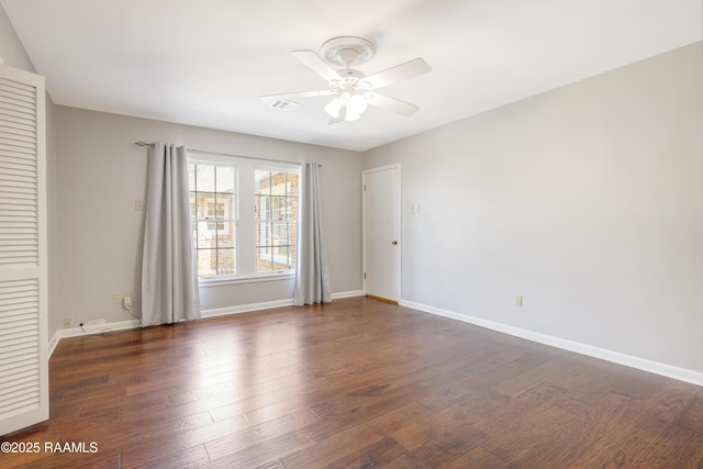 empty room featuring a ceiling fan, wood finished floors, visible vents, and baseboards