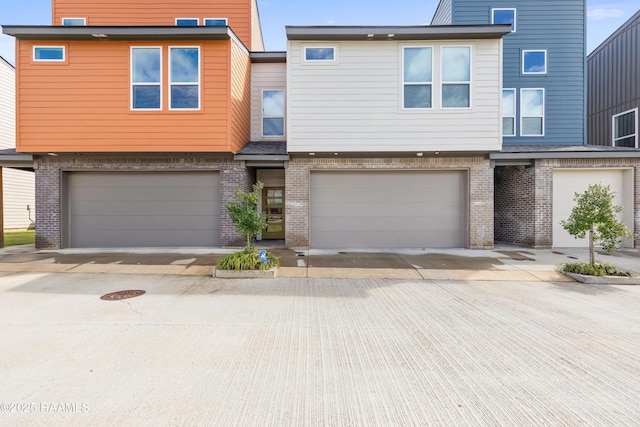 townhome / multi-family property featuring driveway, an attached garage, and brick siding