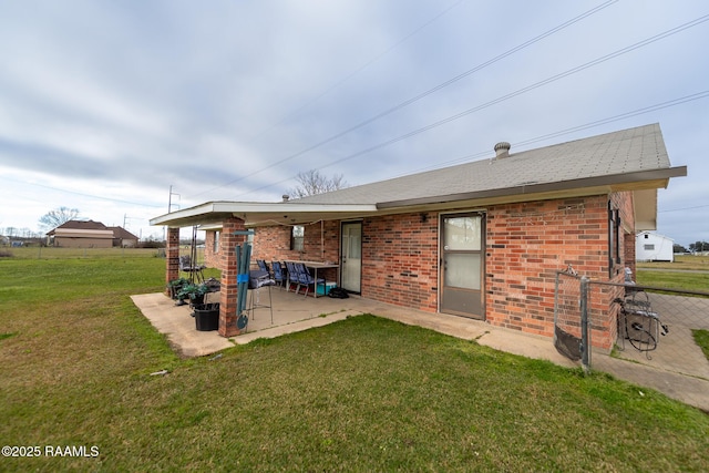 back of property featuring a patio area, brick siding, a yard, and fence