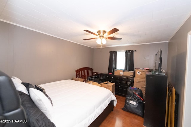 bedroom with ornamental molding, wood finished floors, and a ceiling fan