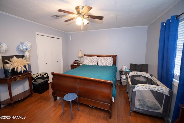 bedroom featuring a closet, visible vents, crown molding, and wood finished floors