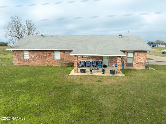 back of house with a patio, brick siding, a lawn, and fence