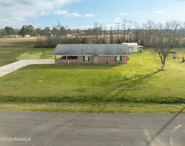 view of front facade featuring a front yard, brick siding, driveway, and a rural view