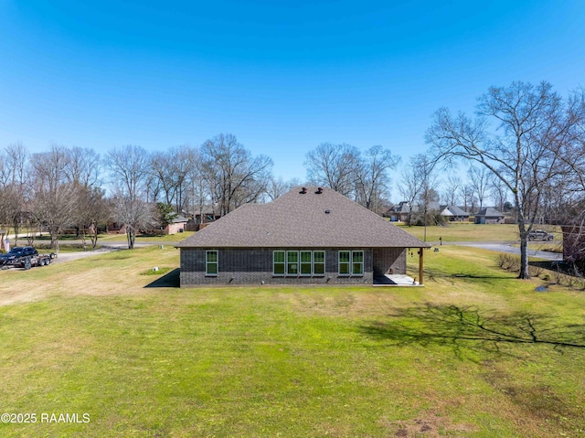 back of house with a yard and a shingled roof