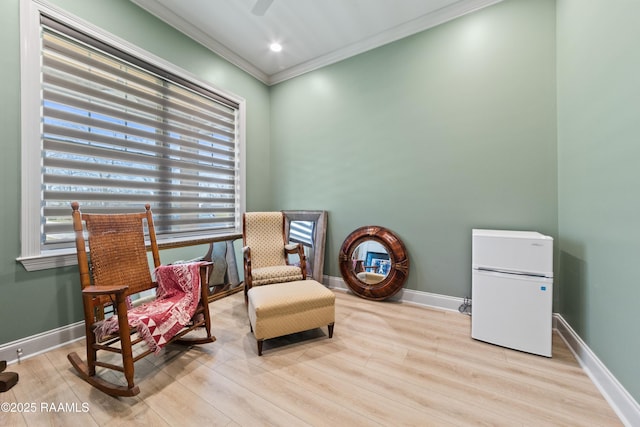 sitting room with light wood finished floors, ornamental molding, and baseboards