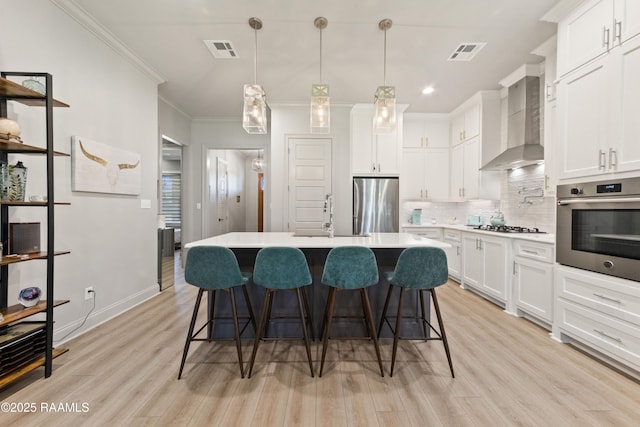 kitchen with stainless steel appliances, light countertops, visible vents, a sink, and wall chimney exhaust hood