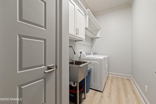 laundry area with baseboards, light wood-style floors, ornamental molding, independent washer and dryer, and cabinet space