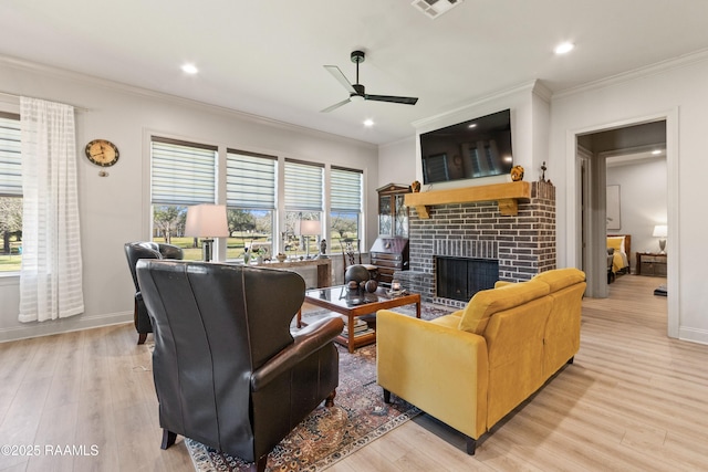 living area with light wood-style floors, a fireplace, and crown molding