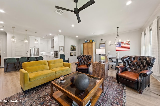 living area with light wood-style floors, recessed lighting, visible vents, and crown molding