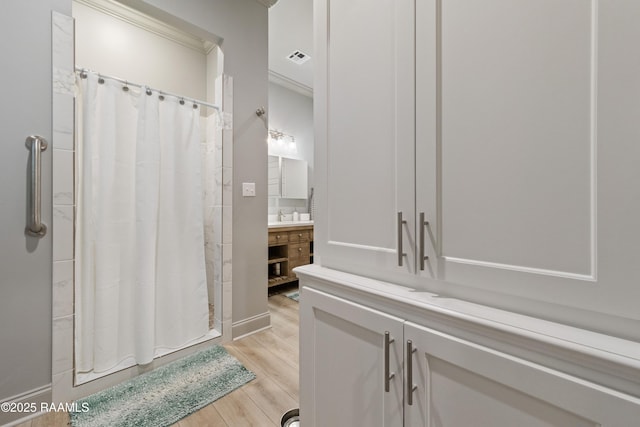 bathroom featuring visible vents, ornamental molding, a stall shower, vanity, and wood finished floors