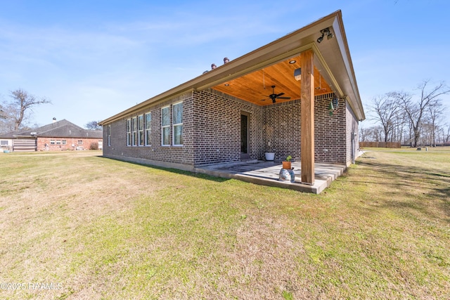 back of house featuring brick siding, a lawn, a patio area, and a ceiling fan