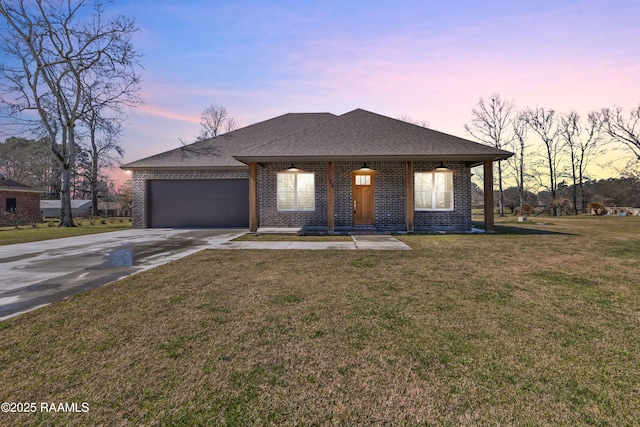 view of front of home with brick siding, roof with shingles, a front yard, a garage, and driveway