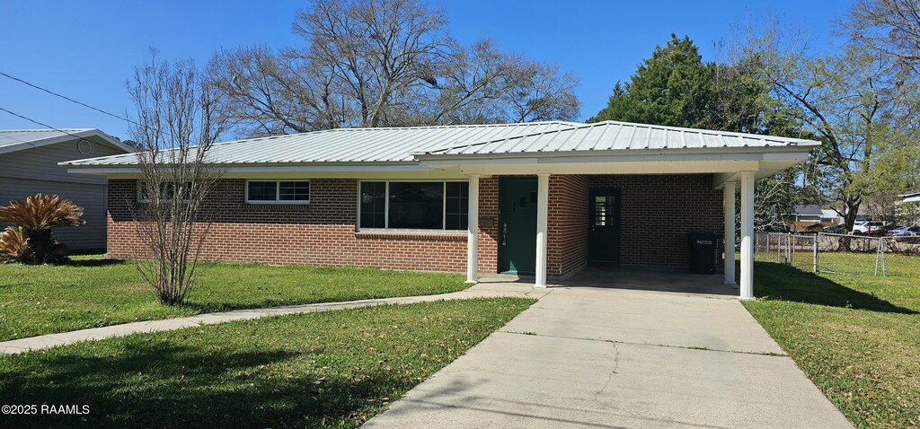 307 Victory Dr, New Iberia, LA 70563 - ranch-style house featuring concrete driveway, brick siding, metal roof, and a front lawn