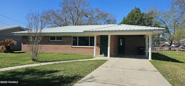 ranch-style house featuring concrete driveway, brick siding, metal roof, and a front lawn