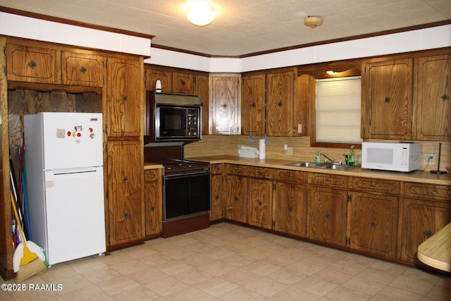 kitchen featuring brown cabinetry, a sink, and black appliances