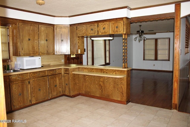 kitchen with ceiling fan, light floors, white microwave, and brown cabinets