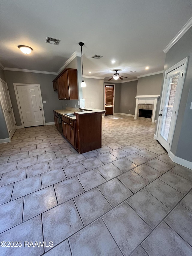 kitchen featuring visible vents, open floor plan, light countertops, ornamental molding, and a tiled fireplace