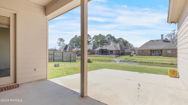 view of patio / terrace with a residential view, a water view, and fence