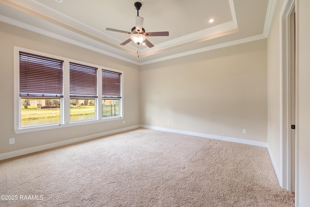 spare room with baseboards, ceiling fan, a tray ceiling, crown molding, and carpet floors