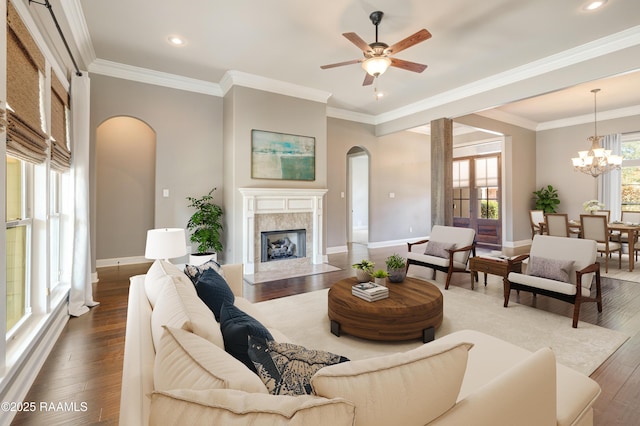 living room featuring dark wood-type flooring, a healthy amount of sunlight, crown molding, and a premium fireplace