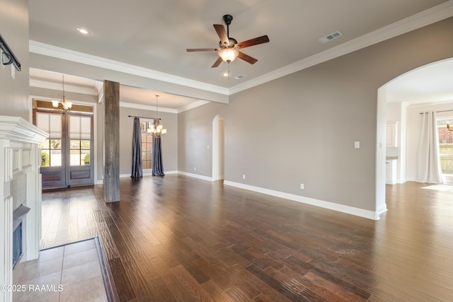 unfurnished living room with arched walkways, dark wood-style flooring, visible vents, and plenty of natural light